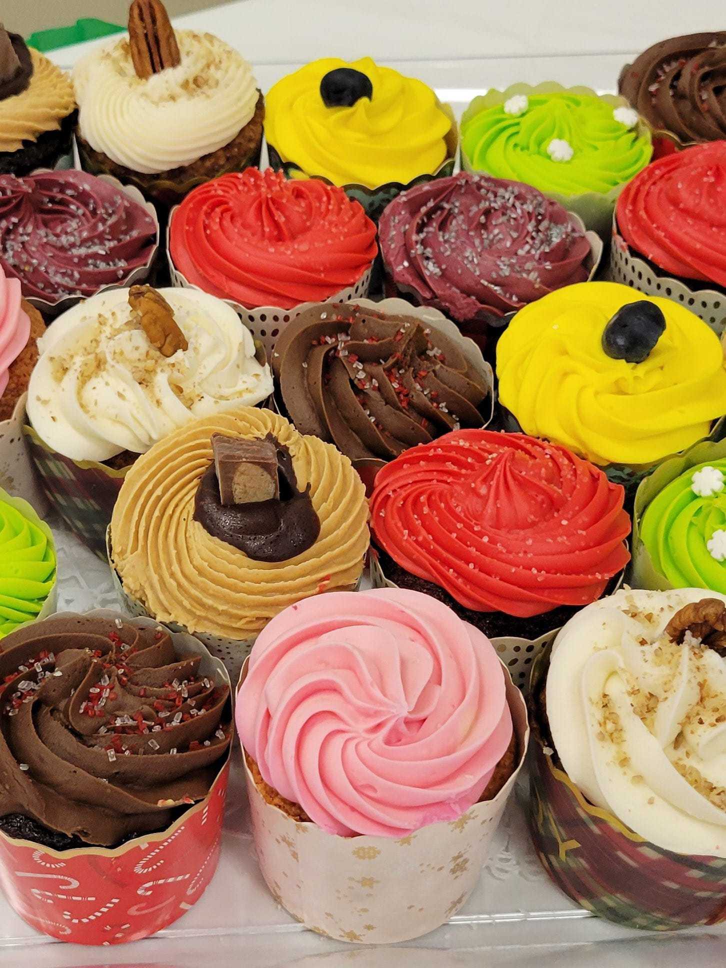 A variety of colorful, decorated cupcakes on display in wrappers.