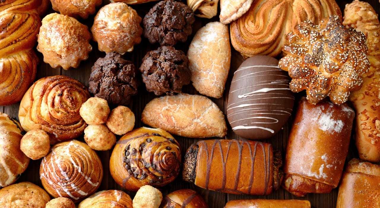 Assorted bakery pastries and cookies arranged on a wooden surface.